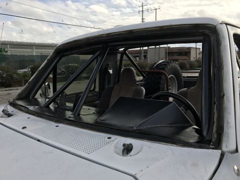 1990 Ford Bronco - Photo of a pickup truck cab fitted with a roll cage and racing seats, not a technical document.