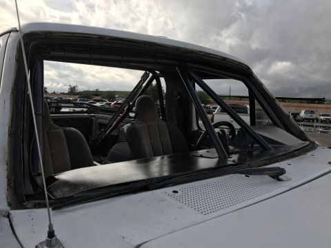 1990 Ford Bronco - Photo of a caged pickup truck cab with racing seats at a track, not a technical document.