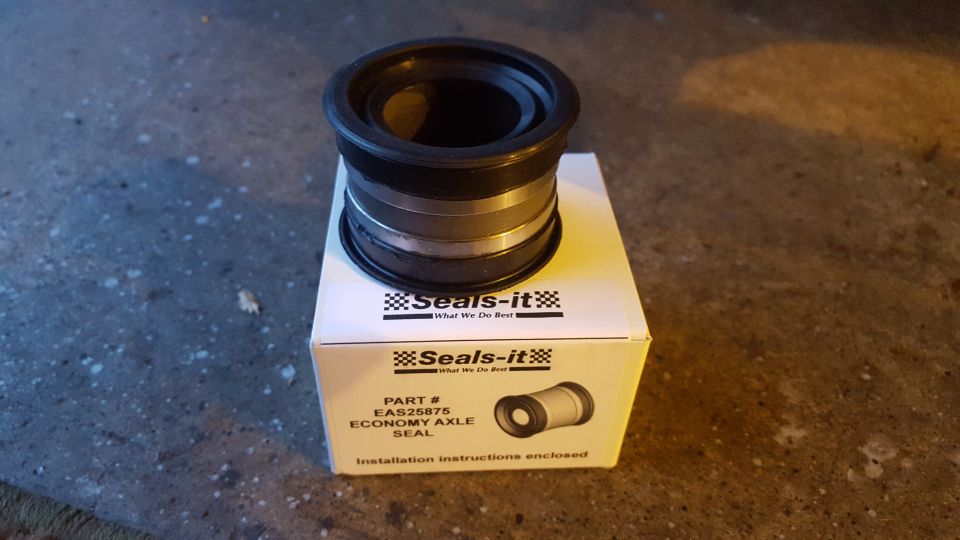 Black cylindrical part with metal banding, sitting on a white cardboard box with some text