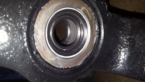 1994 Ford Bronco - This is a close-up, angled shot of a bearing housing within a black metal component, likely part of a vehicle's suspension or drivetrain. T…