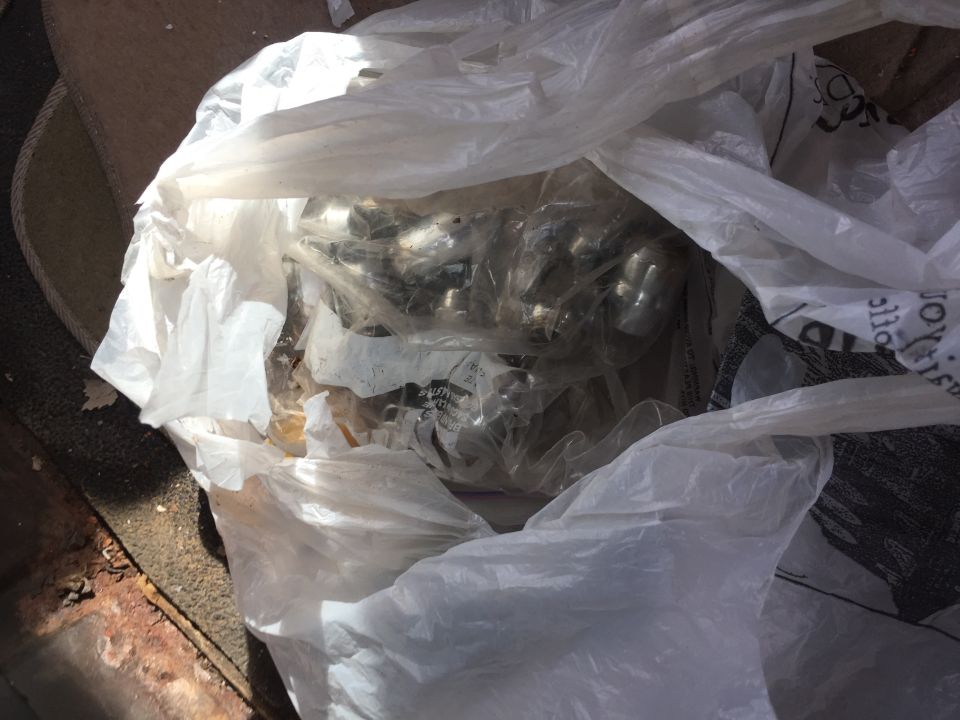 plastic bag filled with metal parts, some appear to be exhaust manifold bolts