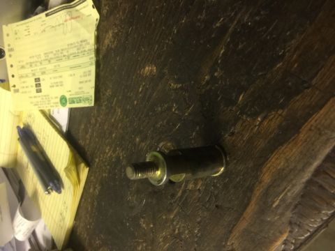 2000 Ford E350 - Bolt and bushing assembly on a wooden surface, with paperwork and pens nearby.