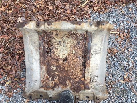 1979 Ford Bronco - A heavily corroded metal component lies on the ground, showing signs of wear and tear.