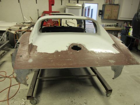 1976 Chevrolet Corvette - The rear of a car body, likely a Corvette, is shown on a stand with primer and body filler applied, indicating repair work.
