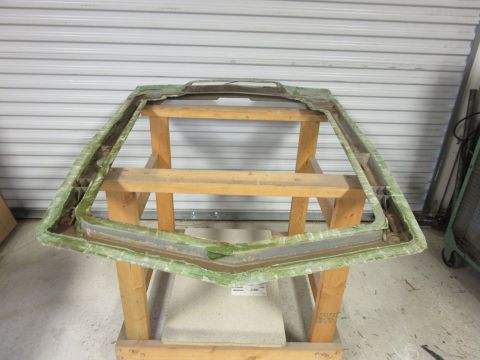 1976 Chevrolet Corvette - Windshield frame assembly, likely fiberglass, supported by wooden sawhorses in a garage.