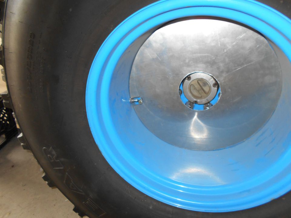 Close-up of a blue-rimmed tire with a silver hubcap.