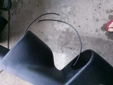 1996 Ford Bronco - A black plastic gauge pod with two circular openings is shown on a concrete surface. A thin black wire or tube is draped over the pod.