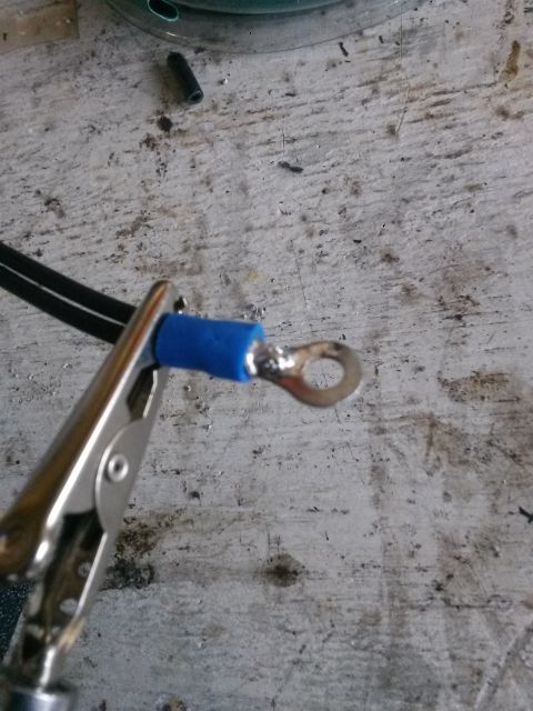1996 Ford Bronco - A close-up shot shows a crimped electrical terminal with a blue insulator being held by a metal clamp. The terminal is attached to a black…