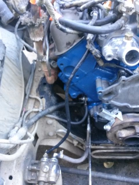 1996 Ford Bronco - A close-up view of a vehicle's engine bay, focusing on the blue-painted engine block and various hoses and components. A metal fuel filter…