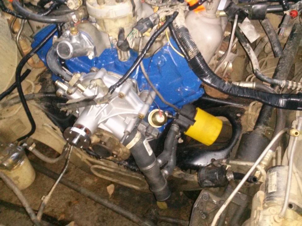 Close-up of a vehicle engine bay showing a water pump and blue intake manifold.