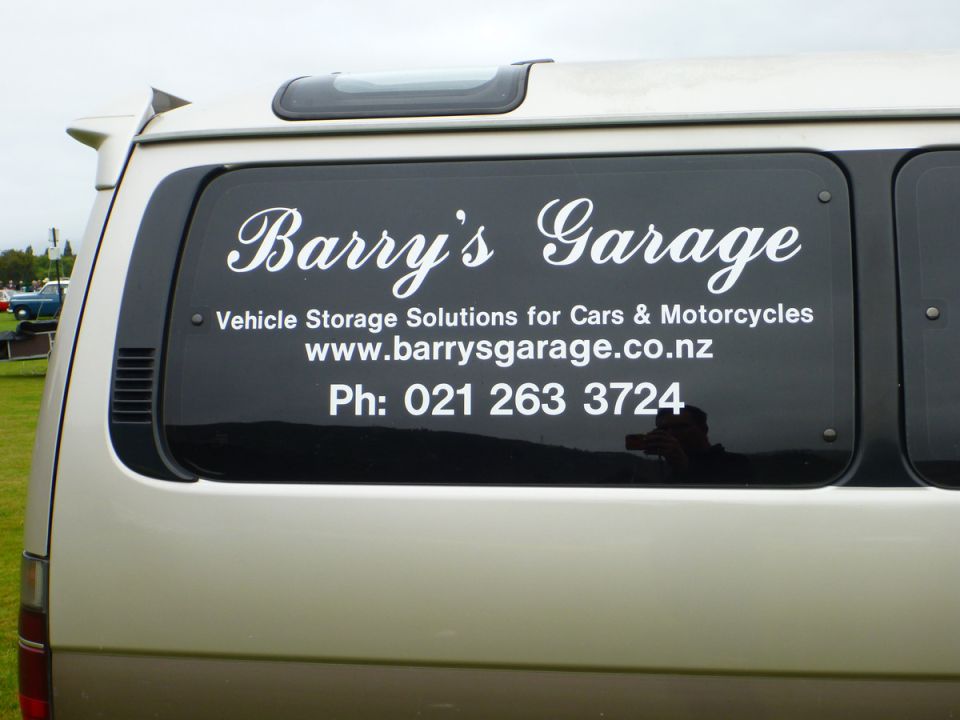 Rear window of a van with white text: Barry's Garage, Vehicle Storage Solutions for Cars & Motorcycles, www.barrysgarage.co.nz, Ph: 021 263 3724.