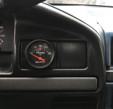 1995 Ford Bronco - A close-up interior shot shows an Auto Meter transmission temperature gauge mounted on the dashboard of a vehicle. The gauge needle is poin…