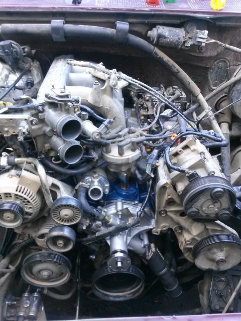 1996 Ford Bronco - Close-up view of the engine bay of a Ford Bronco, showing the engine components, belts, pulleys, and wiring.
