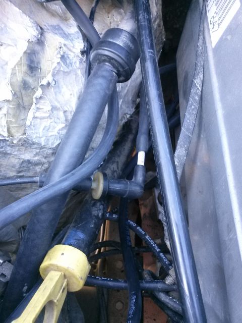 1996 Ford Bronco - Close-up view of various engine hoses and wiring in a vehicle engine bay. A black hose with a yellow fitting is prominent in the foreground…