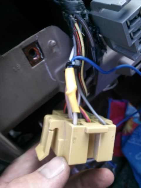 1996 Ford Bronco - A close-up view shows a hand holding a tan electrical connector with several wires attached. The connector is part of a vehicle's wiring ha…