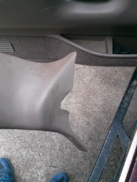 1996 Ford Bronco - A close-up view of the damaged interior plastic trim piece from a 1996 Ford Bronco, resting on a concrete floor next to a person's feet wea…