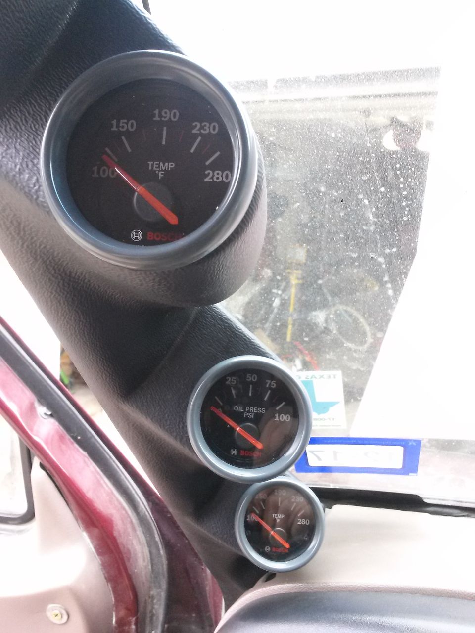 Vehicle interior A-pillar with Bosch temperature and oil pressure gauges.