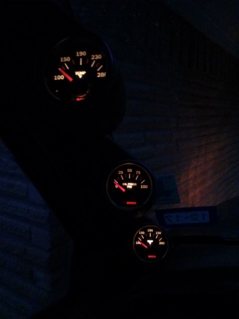 1996 Ford Bronco - Three illuminated Bosch gauges are mounted in a dark interior. The top gauge shows temperature, the middle shows oil pressure, and the bott…