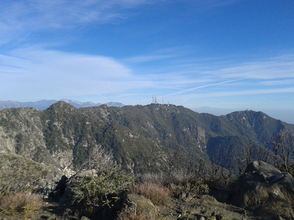 Mountain range with communication towers under a blue sky.
