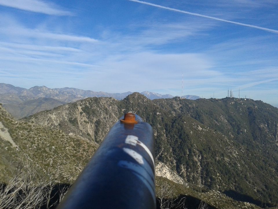 Mountain range with a large metal pipe in the foreground under a blue sky.