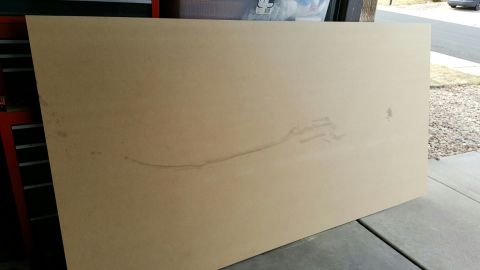 1996 Ford Bronco - A large, light brown sheet of MDF board is leaning against a red toolbox and a garage door. The board has some faint marks and a thin, dark…