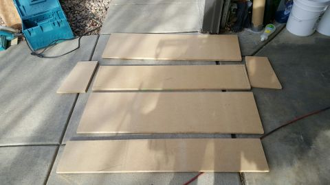1996 Ford Bronco - Several pieces of cut particle board are laid out on a concrete surface, possibly for a DIY project. A teal toolbox and some tools are visi…