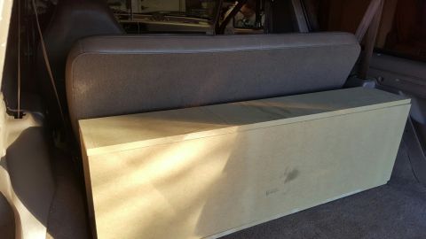 1996 Ford Bronco - A custom-built, unfinished wooden subwoofer box is placed behind the rear seat of a Ford Bronco. The box is positioned on the floor of the…