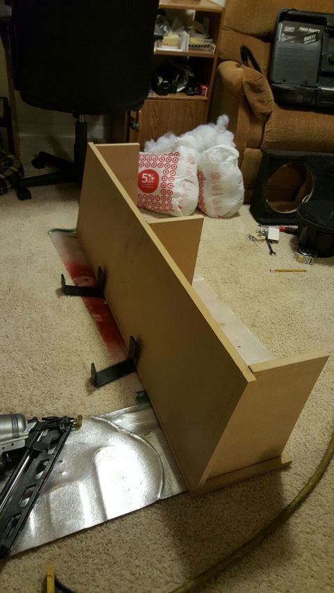 1996 Ford Bronco - A wooden enclosure, possibly for a speaker, is being assembled on a carpeted floor. Tools and materials, including a nail gun, are scattere…