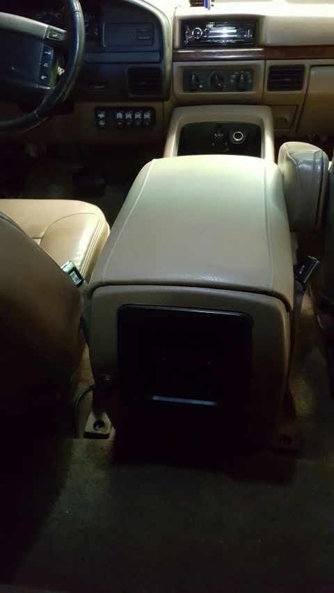 1996 Ford Bronco - The interior of a 1996 Ford Bronco shows the center console and dashboard with a tan leather interior. Visible components include the steer…