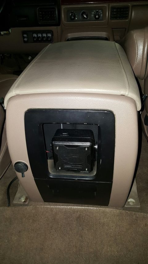 1996 Ford Bronco - A black Uniden speaker is mounted in the center console of a tan interior vehicle. The console has a leather lid and a cubbyhole below the…