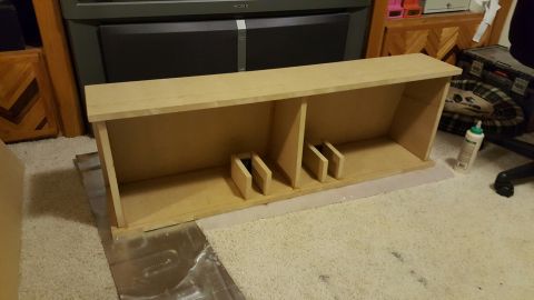 1996 Ford Bronco - A wooden shelf unit with two compartments and two small wooden blocks inside each compartment sits on a carpeted floor. A bottle of glue is…