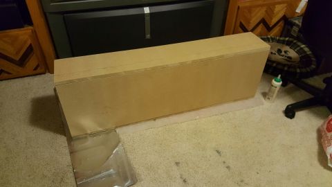 1996 Ford Bronco - A long, rectangular wooden box sits on a carpeted floor. A bottle of glue is next to the box, and a dog bed is visible in the background.