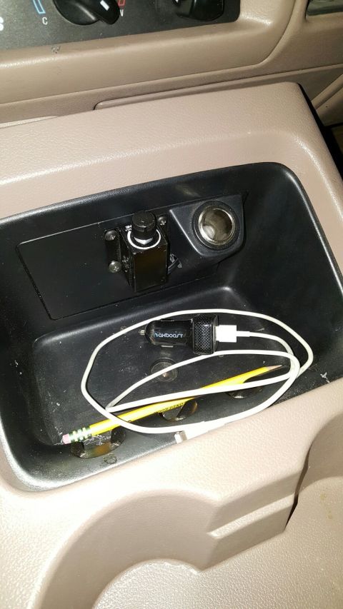 1996 Ford Bronco - A close-up view of a car's center console, showing a 12V power outlet, a custom-mounted dimmer switch, and a USB car charger with a white c…