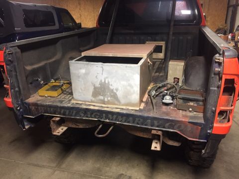 1982 Ford Bronco - The rear of a red pickup truck bed is shown, modified with a large metal tank and wooden supports. Text reading "TULSAGAMMARAY.COM" is visi…