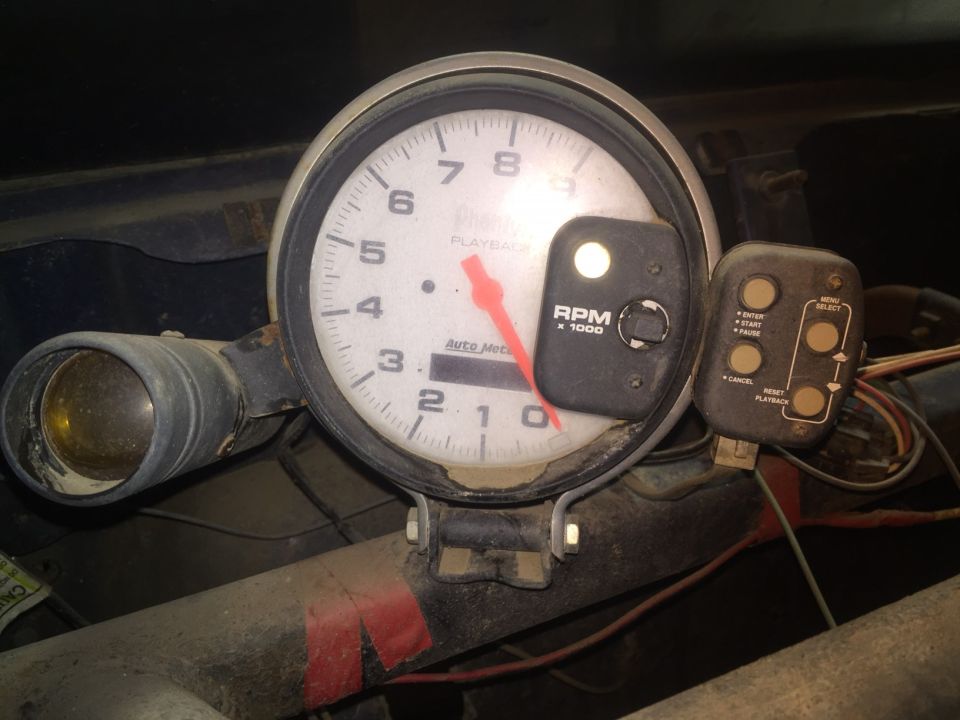 Close-up of a tachometer gauge with RPM x 1000 and playback controls.