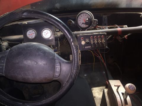 1982 Ford Bronco - The interior of a modified vehicle shows a steering wheel with a Ford logo, a dashboard with multiple gauges, and a switch panel with label…