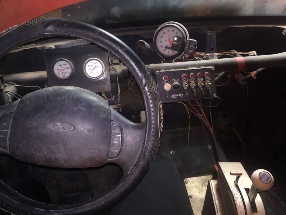 Interior of a modified vehicle with racing gauges, switches, and shifter.