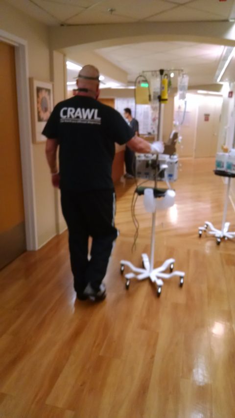 1985 Jeep CJ7 - A person wearing a black t-shirt with the word "CRAWL" on the back and a hat walks down a hospital hallway. The person is pushing a medical…