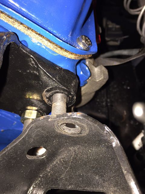 1978 Ford Bronco - A close-up view shows a blue component bolted to a black bracket with a gasket in between. A threaded bolt passes through the bracket, secu…