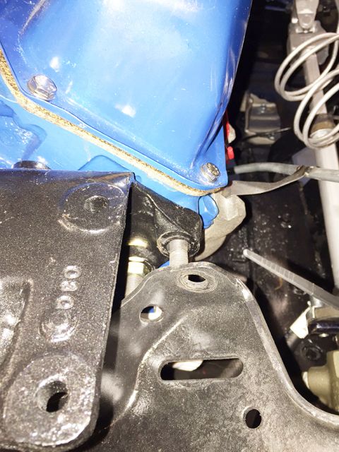 1978 Ford Bronco - A close-up view shows a blue engine component bolted to a black bracket, with a gasket visible between the two parts. The bracket is attach…