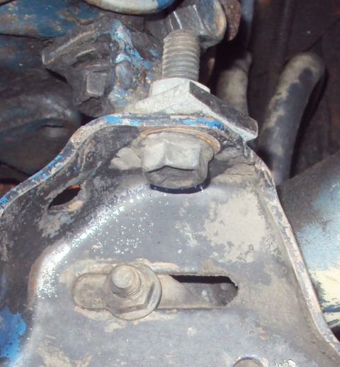 1978 Ford Bronco - A close-up view shows a heavily rusted and dirty metal bracket with several bolts and nuts. The bracket appears to be part of a vehicle's s…