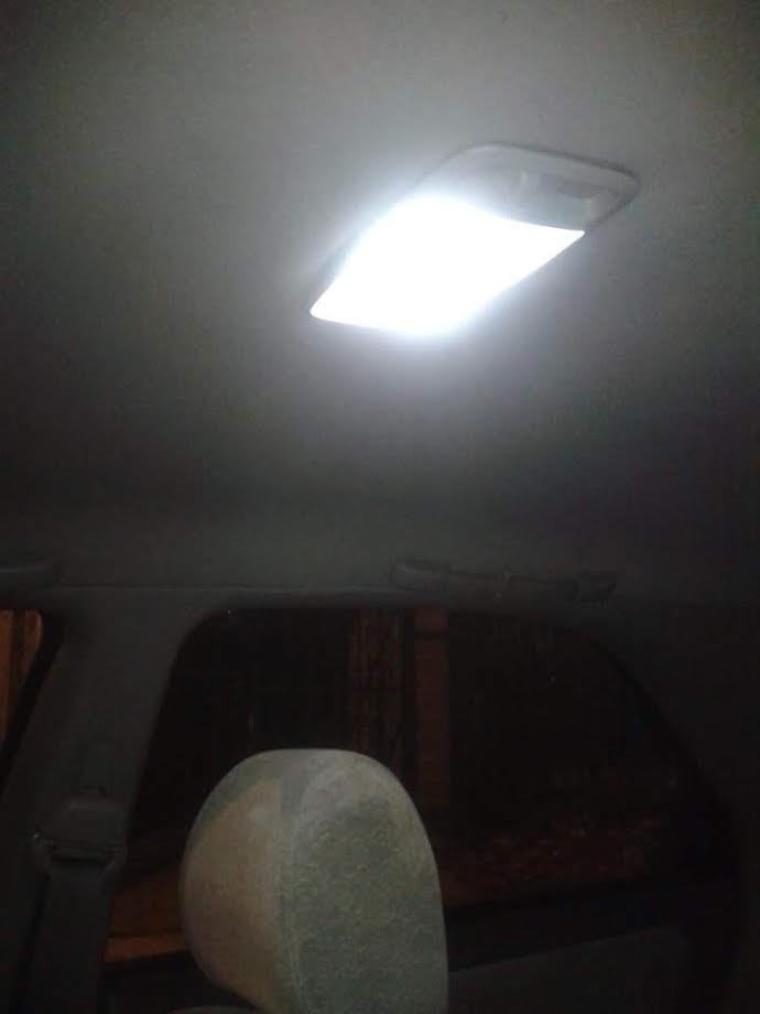Interior of a car at night with the overhead dome light on.