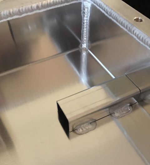 1995 Ford Bronco - A close-up view of the interior of a metallic box with visible welds along the edges and a square metal tube extending from one side.