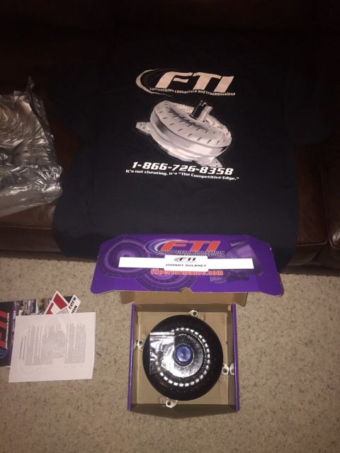 1982 Ford Bronco - A black FTI t-shirt with a graphic of a torque converter and contact information is laid out on a carpeted surface next to an open box cont…