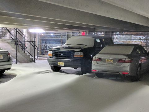 1995 Ford Bronco - A black Ford Bronco and a silver sedan are parked under a concrete structure, covered in snow. The Bronco's license plate reads "K55 FKT".