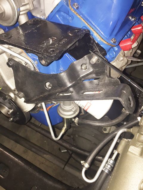 1978 Ford Bronco - This is a close-up view of a black metal engine bracket attached to a blue engine block. A fuel filter and fuel lines are also visible.