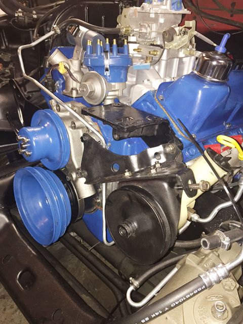 1978 Ford Bronco - A close-up, angled view of a blue and silver V8 engine, likely from a 1978 Ford Bronco, showing the distributor, carburetor, pulleys, and p…