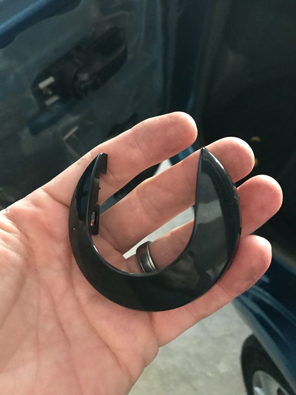 Black plastic trim piece held in hand, with a car interior in the background.