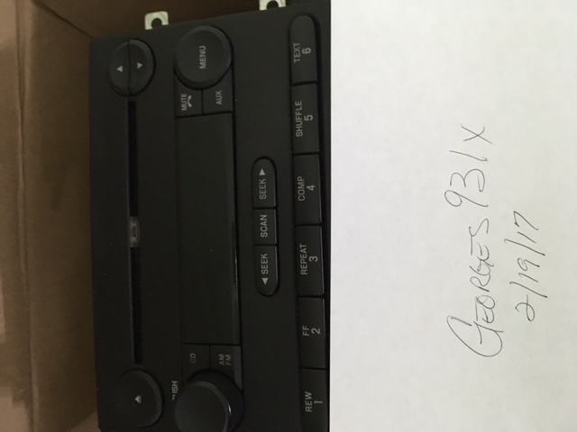 Black car radio with various buttons and handwritten text below.