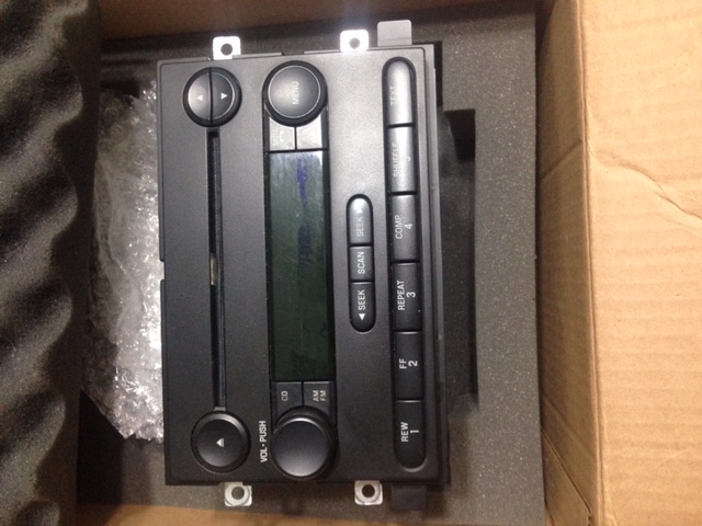 Car stereo head unit with buttons and display, in a box.